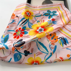 Close-up of floral print silk scarf with vibrant orange and blue flower details