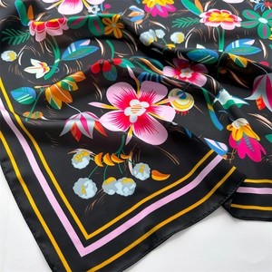Detail of vibrant floral print on smooth silk-like satin fabric of a black square scarf