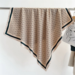 Close-up of champagne silk scarf with black geometric ring patterns and border