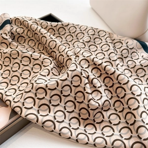Close-up of geometric ring print silk scarf with champagne gold sheen and green border