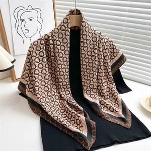 Elegant 90cm silk scarf with interlaced chain print draped over a black knit sweater