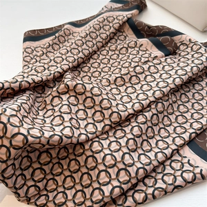 Detail of silk-like scarf with rose pink geometric chain print and premium hemmed edges