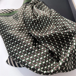 Détail d'un foulard en soie avec motif géométrique H vert et marron et bordure rayée
