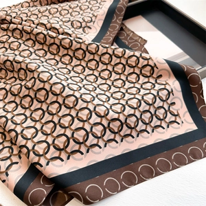 Detailed view of luxury silk scarf with interlocking chain print and soft pink edges