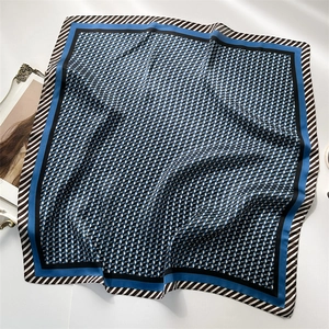 Carré de soie de 70cm à motif géométrique bleu foncé avec bordure rayée sur une table blanche