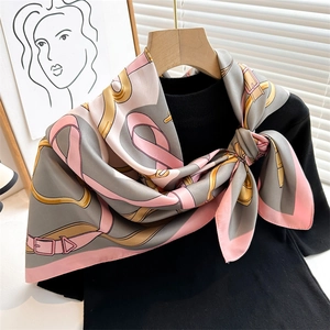Detail of silk-feel scarf with equestrian print draped over a black knit sweater