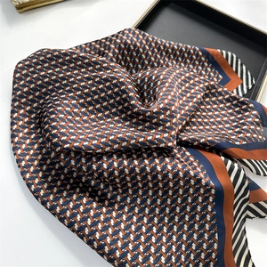 Gros plan d'un foulard en soie avec motif géométrique H orange et bleu marine chic