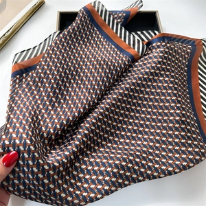 Détail d'un foulard en soie satinée avec motifs géométriques orange et bleu marine
