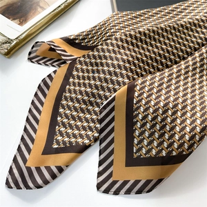 Détail d'un foulard en soie avec motif en H de luxe et texture satinée sur table blanche