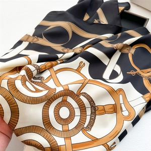 Close-up of equestrian silk scarf showing detailed belt, gold chain, and buckle patterns