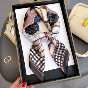 Détail d'un foulard en soie à imprimé camélia et pied-de-poule dans son coffret