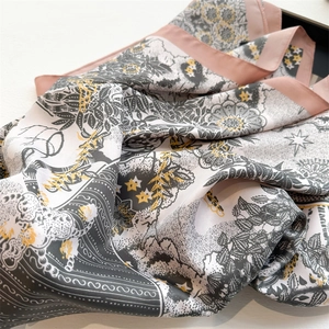 Detailed close-up of a premium sunflower print silk scarf with pink borders and leaf patterns