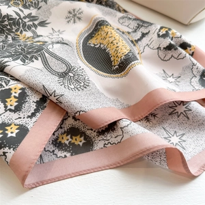 Detailed close-up of premium silk scarf featuring tiger and pine tree print patterns