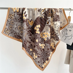 Detail of printed silk scarf with floral and celestial patterns hanging on a metal rod
