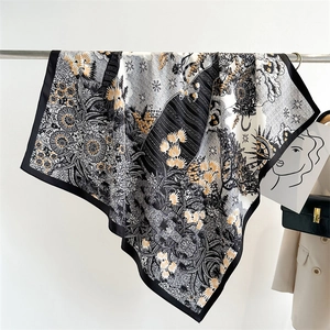 Close-up of a luxury silk scarf with black gold sunflower print draped on a metal rack