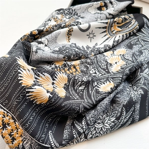 Detailed view of silk scarf with golden sun and tropical patterns on satin fabric