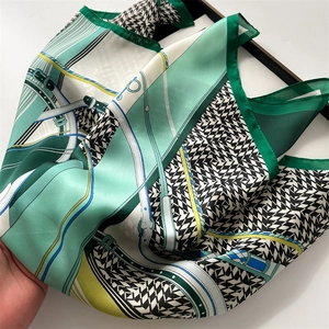 Detail of emerald green silk scarf with houndstooth print and elegant satin texture