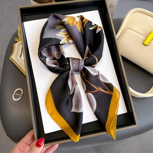 Floral print silk scarf with sunflower and autumn leaf patterns on black tray