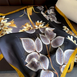 Detailed close-up of floral silk scarf showing elegant satin texture and gold hem edges