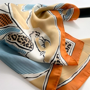 Detail of silk-like scarf featuring leopard print and geometric patterns in orange and blue
