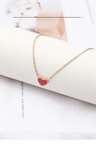 Dettaglio della collana con pendente a cuore rosso in oro rosa su sfondo semplice