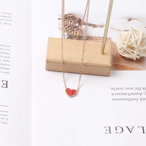 Dettaglio della collana a cuore con smalto rosso e bordo perlato su espositore in legno