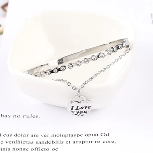 Macro shot of silver heart pendant with I Love You engraving and crystal bracelet