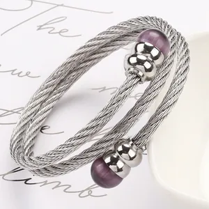 Detail eines gedrehten Edelstahl-Armbands in Silber mit zwei lila Katzenaugenperlen