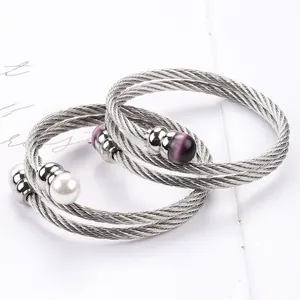 Detail von gedrehten Edelstahldraht-Armbändern mit weißer Perle und lila Katzenaugenperlen