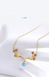 Detail of elk antler necklace in gold with pink crystals and blue teardrop pendant