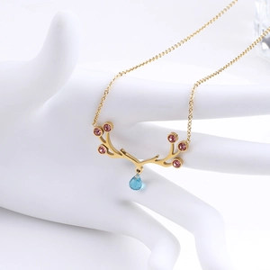 Detail of golden elk antler necklace with pink zircon accents and blue water drop pendant