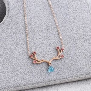 Macro shot of rose gold elk antler pendant with pink rhinestones and blue teardrop gem