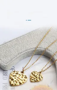 Close-up of golden heart pendants with vintage hammered texture on stainless steel chains