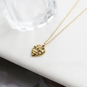 Detailed view of gold-plated heart pendant with unique hammered texture and slim chain