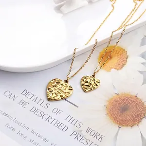 Set of two gold heart necklaces with hammer texture displayed on an elegant white plate