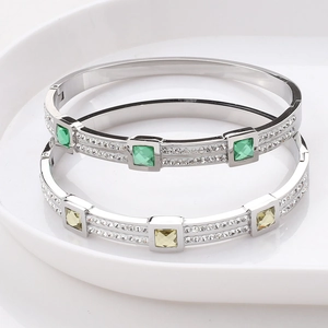 Detailed close-up of crystal-encrusted bangle with green and yellow square-cut center stones