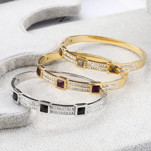 Close-up of stacked stainless steel bangles with pavé crystals and square center stones