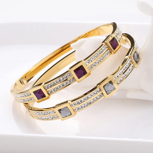 Detail of luxury gold-plated bangle set with square purple and grey gems and micro pavé stones