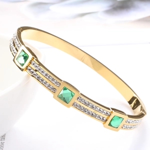 Detail view of gold titanium steel bangle with emerald green zircon and pavé stones