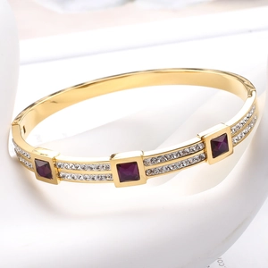 Macro shot of gold-plated bangle featuring square purple gemstones and pave zircon setting