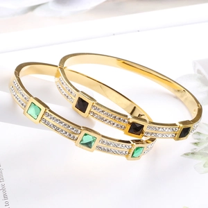 Detail of gold-plated stainless steel bangles with square green and black stones