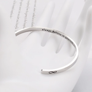 Macro detail of silver stainless steel cuff with infinity symbol and inspirational engraving