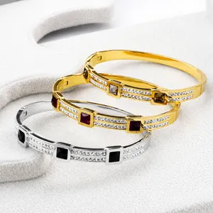 Detailed stack of gold and silver bangles featuring square stones and pavé cubic zirconia
