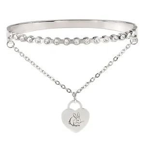Macro detail of silver bangle featuring heart charm with rabbit engraving and cubic zirconia