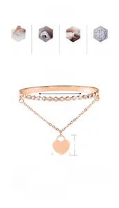 Close-up of rose gold stainless steel bangle with sparkling zircons and heart pendant