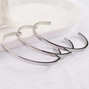 Set of three minimalist polished stainless steel open bangles on a white background