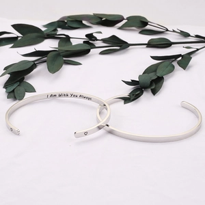 Macro detail of silver stainless steel cuff with engraved 'I Am With You Always' quote