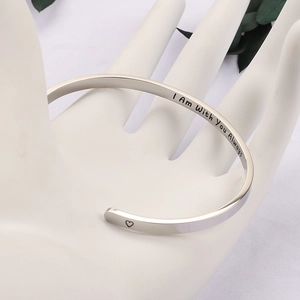 Detail of silver stainless steel bangle engraved with I Am With You Always and heart