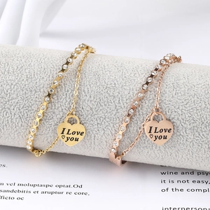 Detailed macro view of heart pendant with I Love You engraving on layered chain bracelet