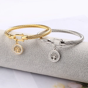 Detail of twisted cable bangles with Tree of Life charms in gold and silver finish